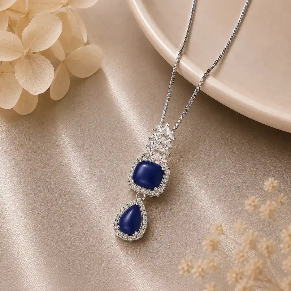 Silver Celestial Drop Pendant Necklace featuring a square and teardrop double-halo pendant set with deep blue stones and sparkling clear zircon crystal accents.