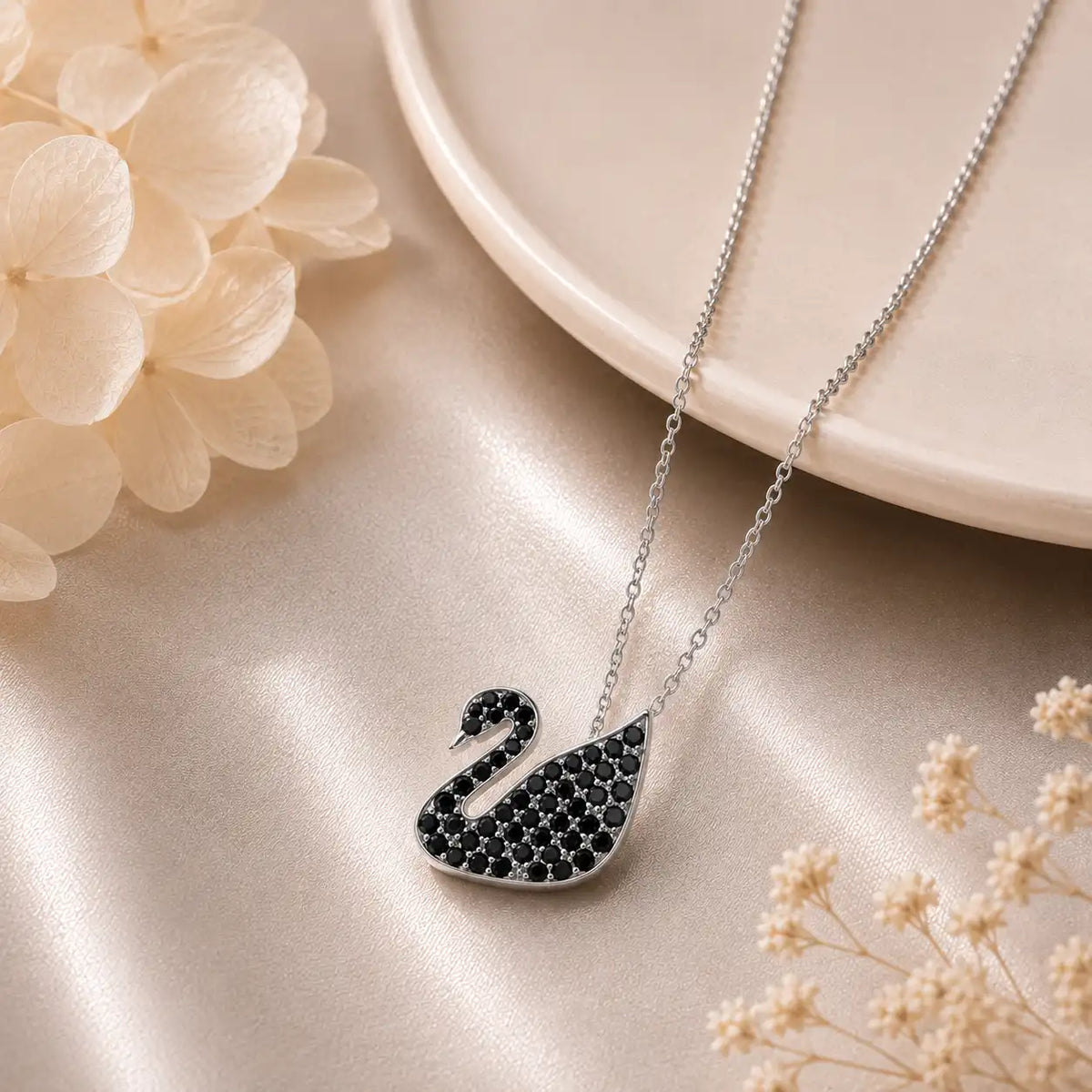 Silver-tone Elegant Swan Crystal Pendant Necklace fully pavé-set with shimmering white crystals, displayed on a soft champagne satin background.