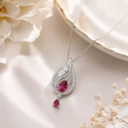 Silver teardrop pendant necklace featuring a pastel pink quartz stone center and a small dangling pink teardrop charm, accented with clear pavé crystals.